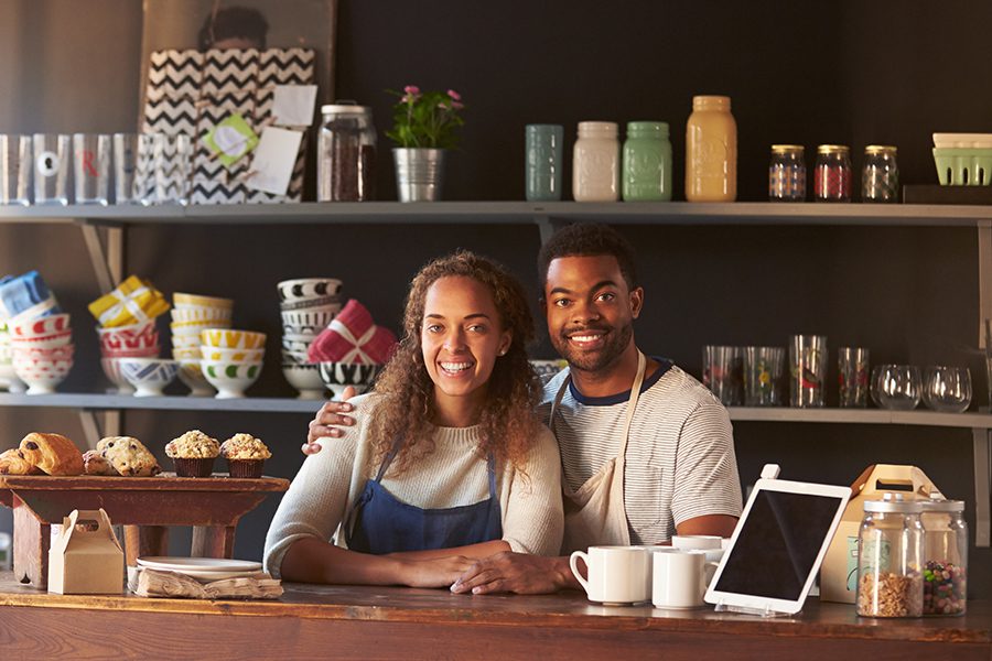 Business Insurance - Happy Smiling Couple Working at The Counter of Their Local Coffee Shop Business