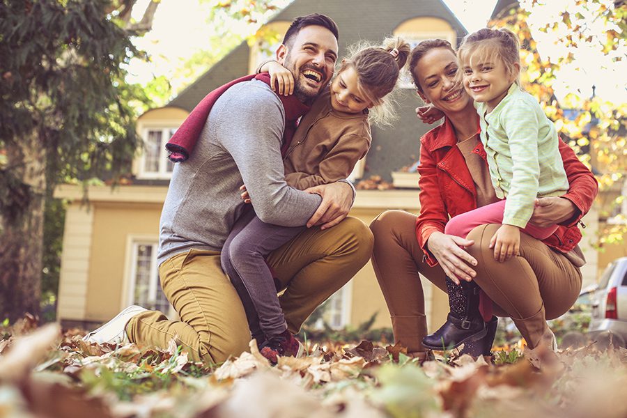 Personal Insurance - Family Having Fun Outside Their Home While Playing in Leaves in the Fall