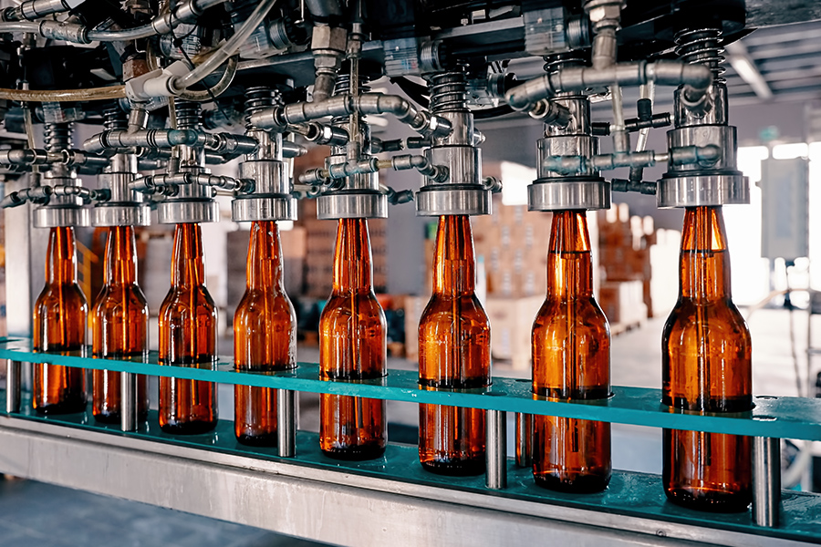 Specialized Business Insurance - Closeup View of Beer Bottles Being Filled on a Conveyor Belt in a Brewery